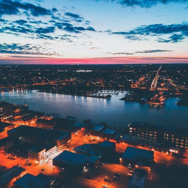 Aerial view of the water in Downtown Bay City at dusk with buildings lit up