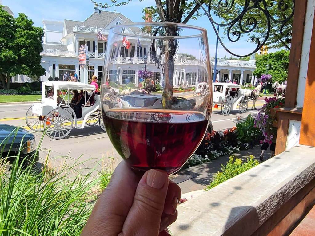 Enjoying a glass of wine on the patio of Bavarian Inn Restaurant while watching a horse-drawn carriage go by in front of Zehnder's of Frankenmuth