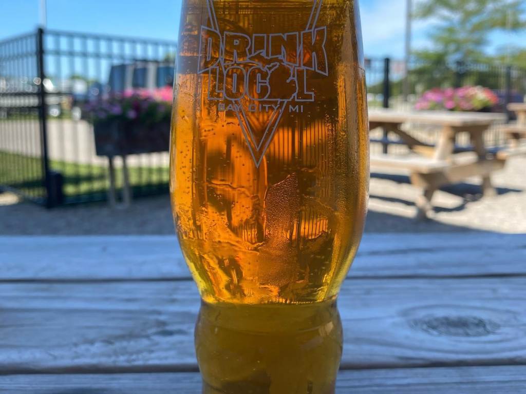 Fresh pour served in a "Drink Local" pint glass on a summery day outside of Tri-City Brewing Company in Bay City