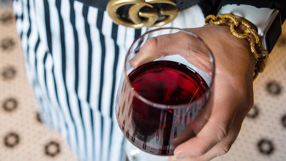 Woman holding a red glass of wine in a black-and-white outfit that matches the tile floor at Prost Wine Bar & Charcuterie in Frankenmuth
