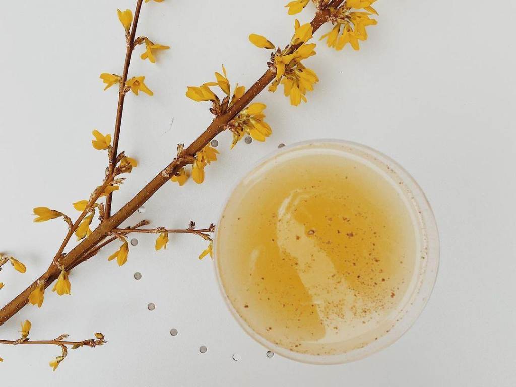 Handcrafted, yellow artisan cocktail next to a yellow flower at The Public House in Bay City