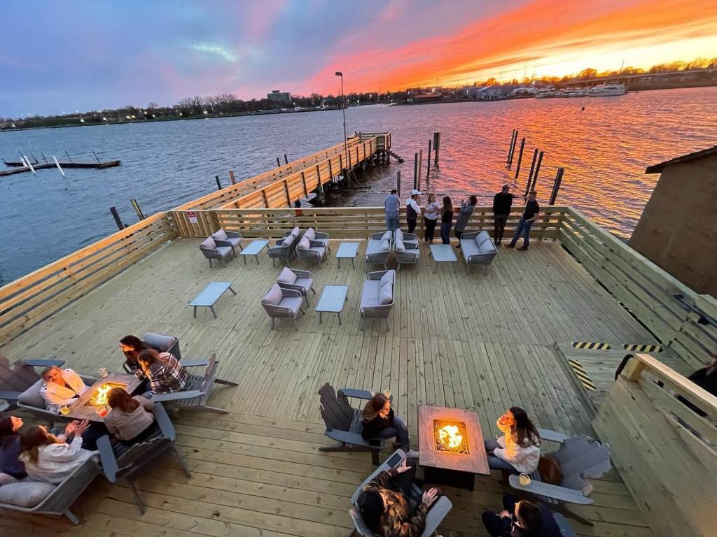 Views of the dockside dining area at Drift Shoreside Beer Garden in Downtown Bay City, with patrons gathered around the fire tables
