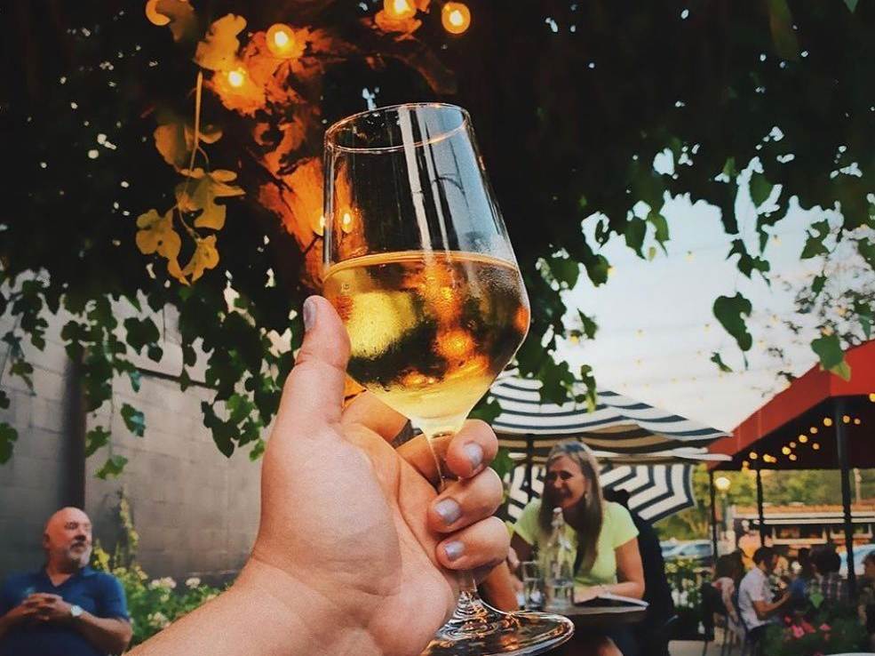Hand raising a glass of wine on the outdoor patio of Prost Wine Bar & Charcuterie in Frankenmuth