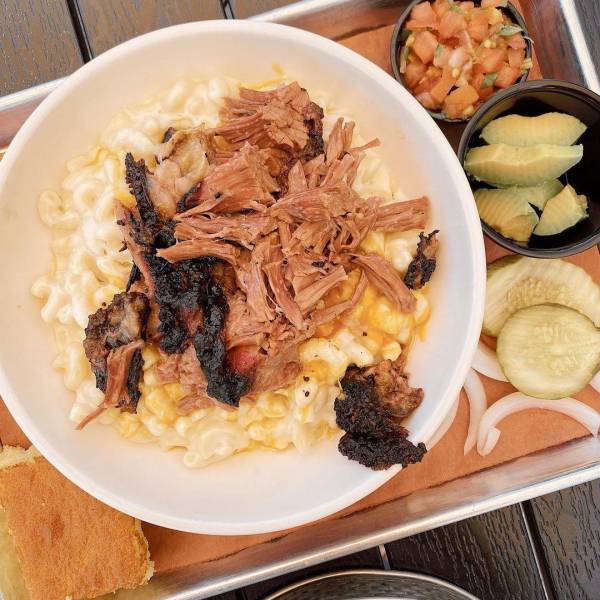 Creamy mac & cheese, chopped brisket burnt ends, a generous dusting of house rub, and fresh pico, served up on an outdoor table at Molasses Smokehouse + Bar in Midland