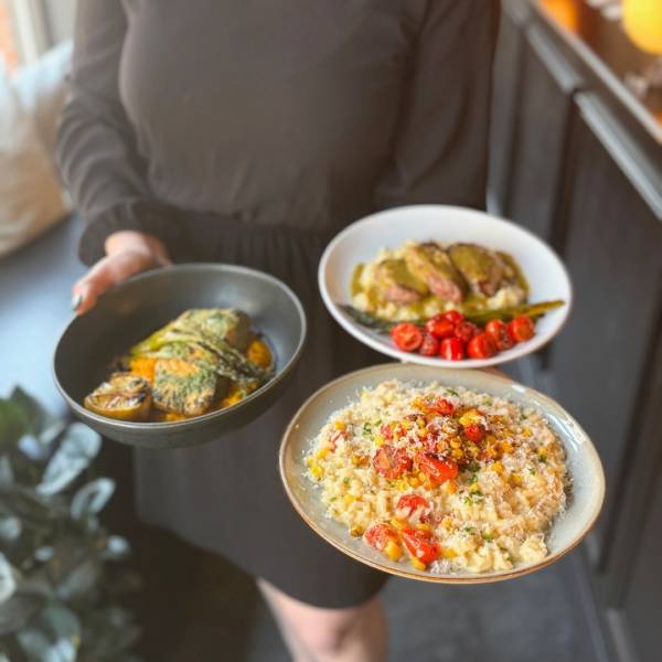 A server holding three beautifully plated dishes at Prost! Wine Bar & Charcuterie in Uptown Bay City, Michigan.