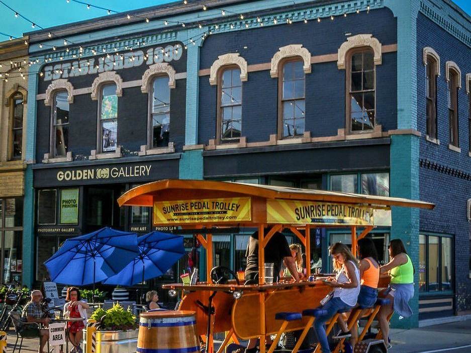 Group of riders on the Sunrise Pedal Trolley, stopped by the Third Street Star Bridge during Feet on the Street in Bay City