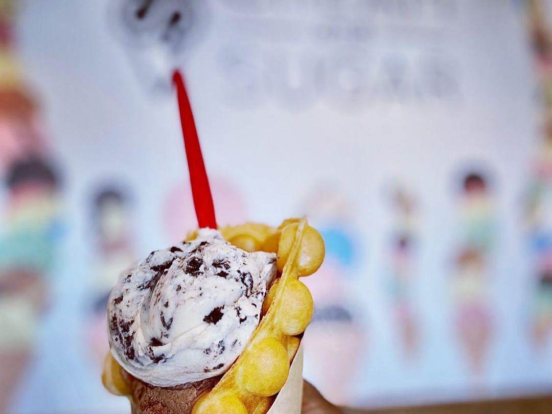 Double-scoop bubble waffle cone in front of the ice cream mural at Cream & Sugar Ice Cream Company in Uptown Bay City