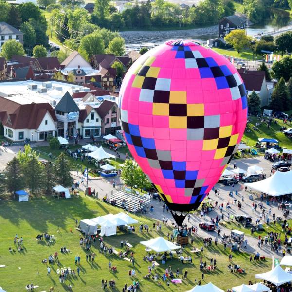 A bright pink hot air balloon flying over the festival during Balloons Over Bavarian Inn in Frankenmuth