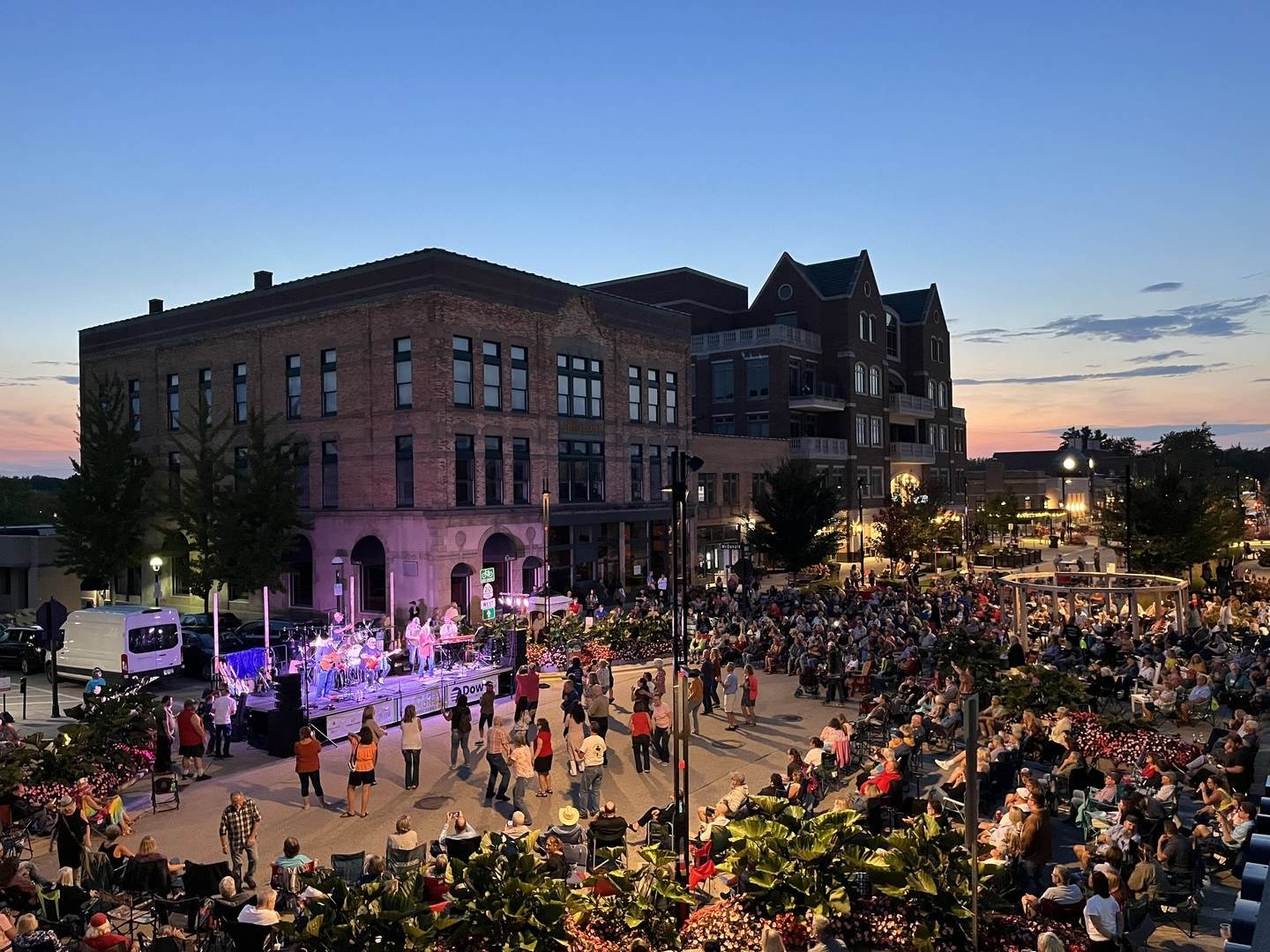 Views of the crowd gathered in the city streets at dusk for The Commons Live Music Series in Downtown Midland, Michigan