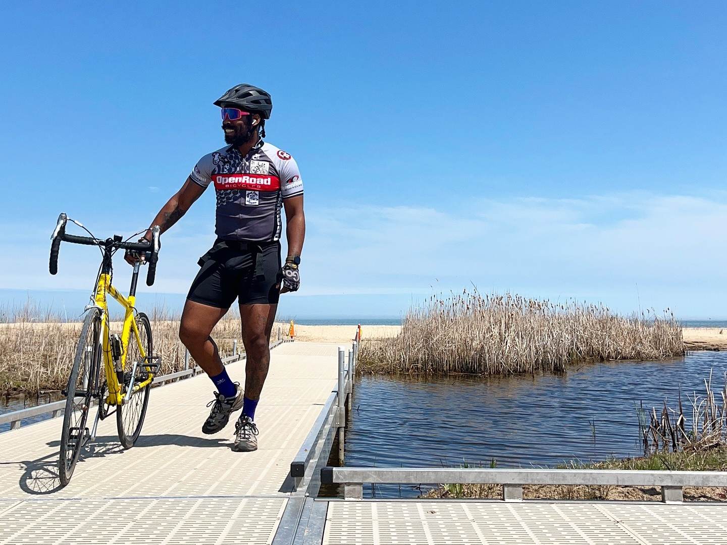 A cyclist posing on a beautiful boardwalk with their road bike while riding the forest trails and along the Saginaw Bay shoreline at Bay City State Park in Bay City, Michigan.