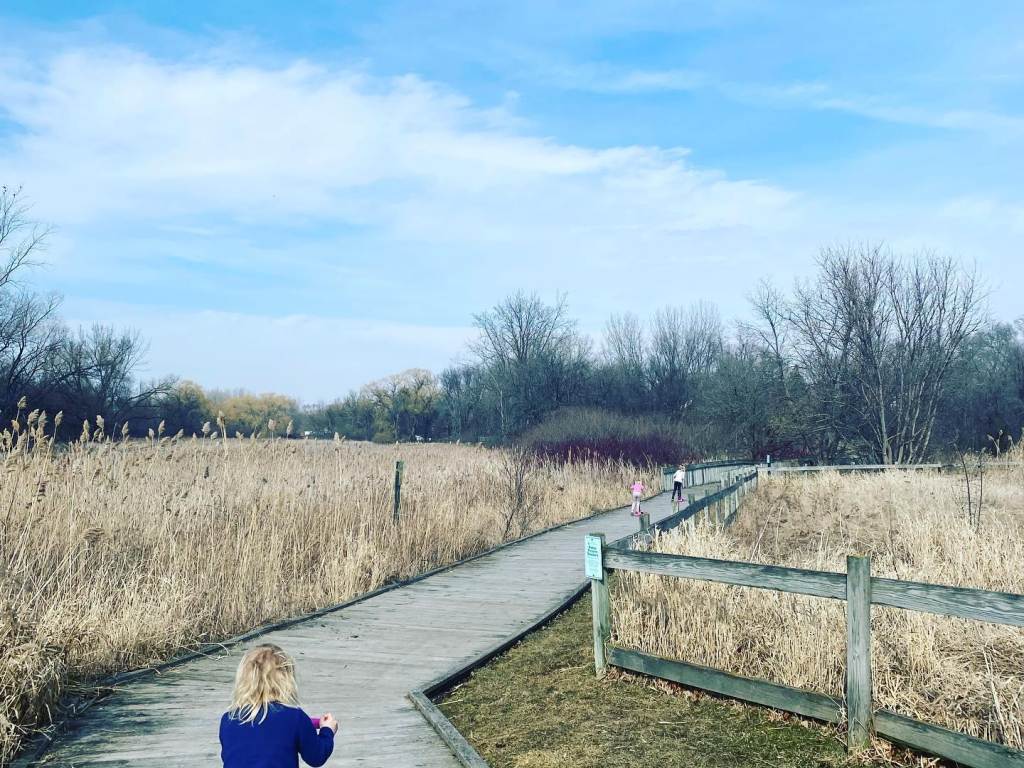 A child riding a scooter on the wooden boardwalk trail at Discovery Preserve in Bay City on a beautiful early-spring day