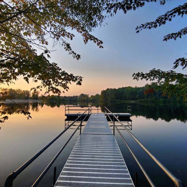 View from a dock overlooking trees reflecting off the water at Stratford Woods Park in Midland