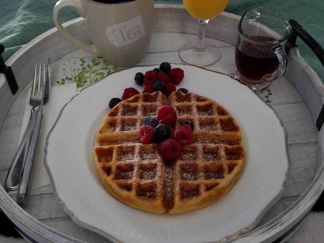 Waffles topped with fresh berries and a side of tea and orange juice at Frankenmuth Country Bed & Breakfast in Frankenmuth