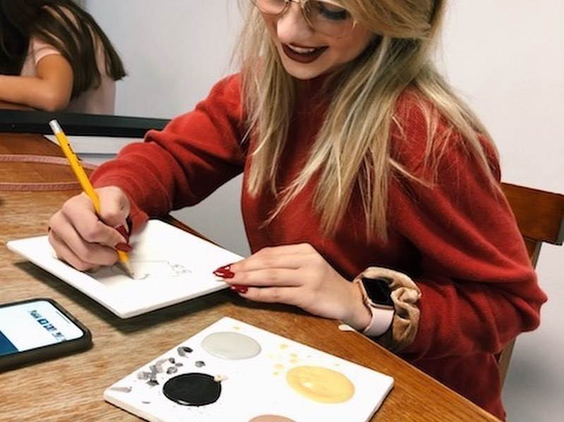 Woman smiling while painting pottery at Painterly Pottery in Bay City