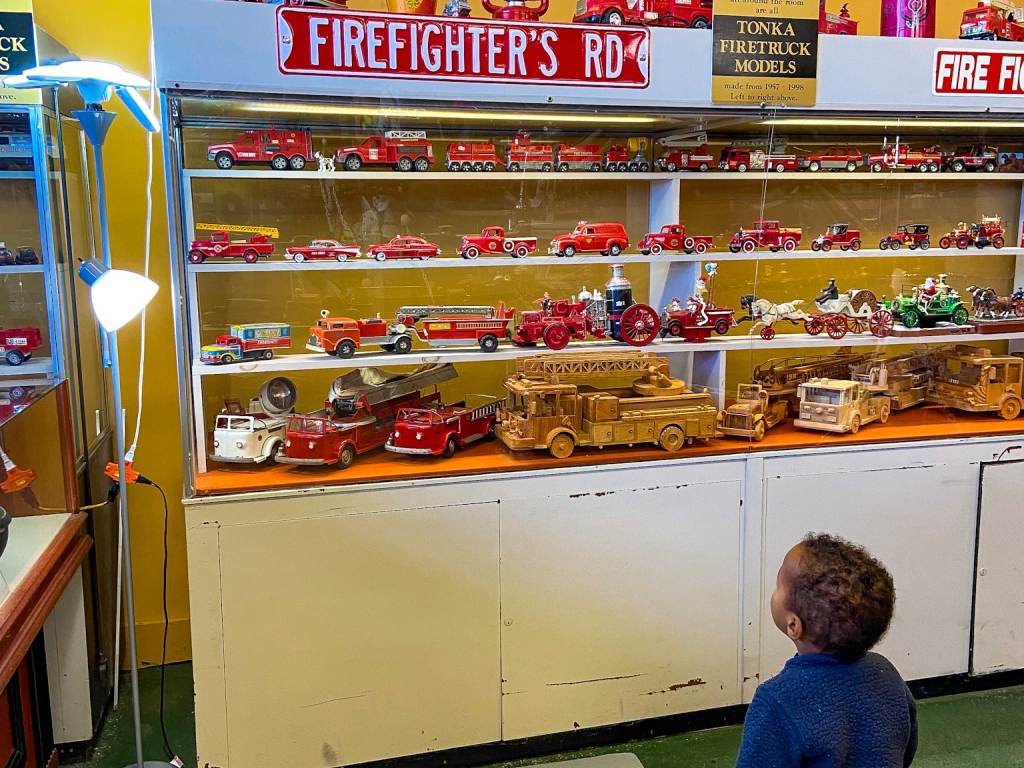 A child looking up in wonder at the fire truck toy displays inside the Antique Toy and Firehouse Museum in Bay City