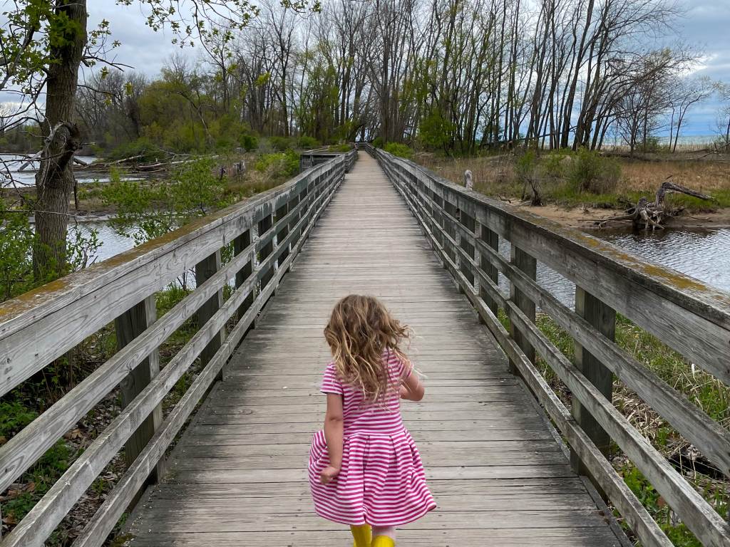 Little girl running on a boardwalk trail at Bay City State Park in Bay City