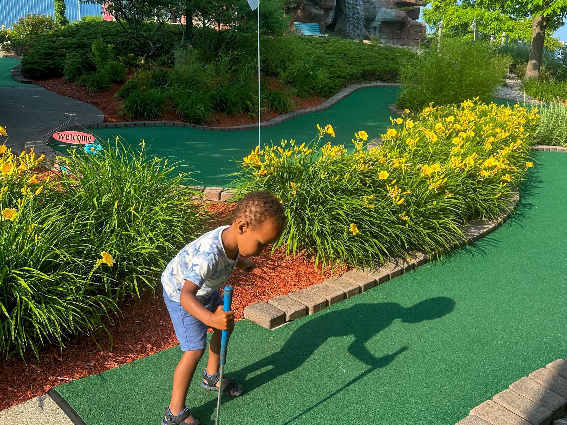 Child playing putt-putt golf on a sunny day at Buoy 18 Miniature Golf, Arcade & Ice Cream Shop along the Saginaw River in Bay City