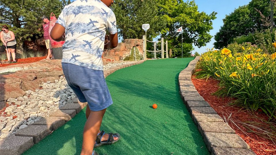 Child playing putt-putt golf on a sunny day at Buoy 18 Miniature Golf, Arcade & Ice Cream Shop along the Saginaw River in Bay City