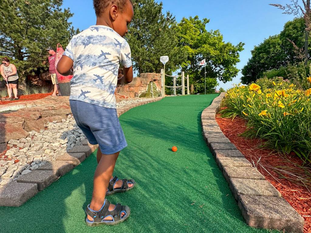 Child playing putt-putt golf on a sunny day at Buoy 18 Miniature Golf, Arcade & Ice Cream Shop along the Saginaw River in Bay City
