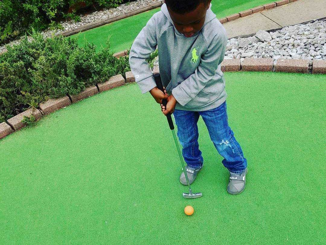 Little boy putting on the outdoor mini-golf course at Alpine Mountain in Birch Run