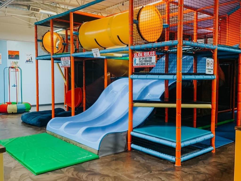 A triple slide that's part of the giant, colorful indoor play structure at The Playground in Midland