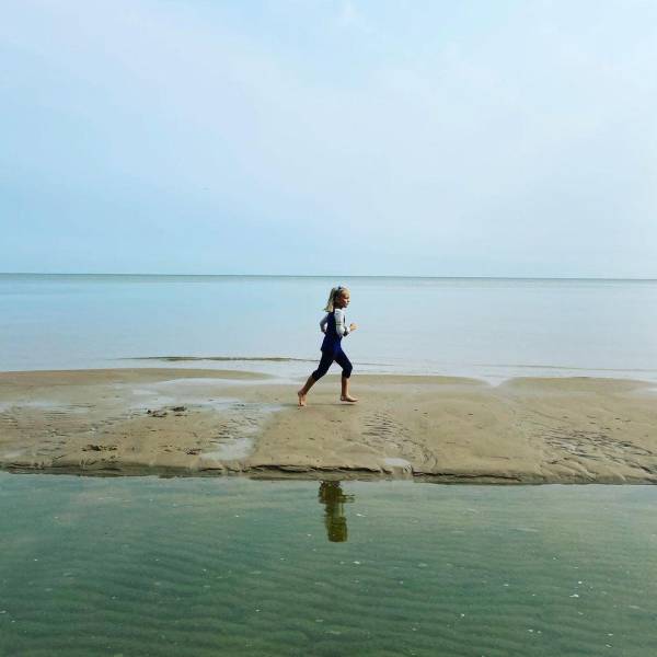 Little girl running on the sandy beachfront at Bay City State Park in Bay City