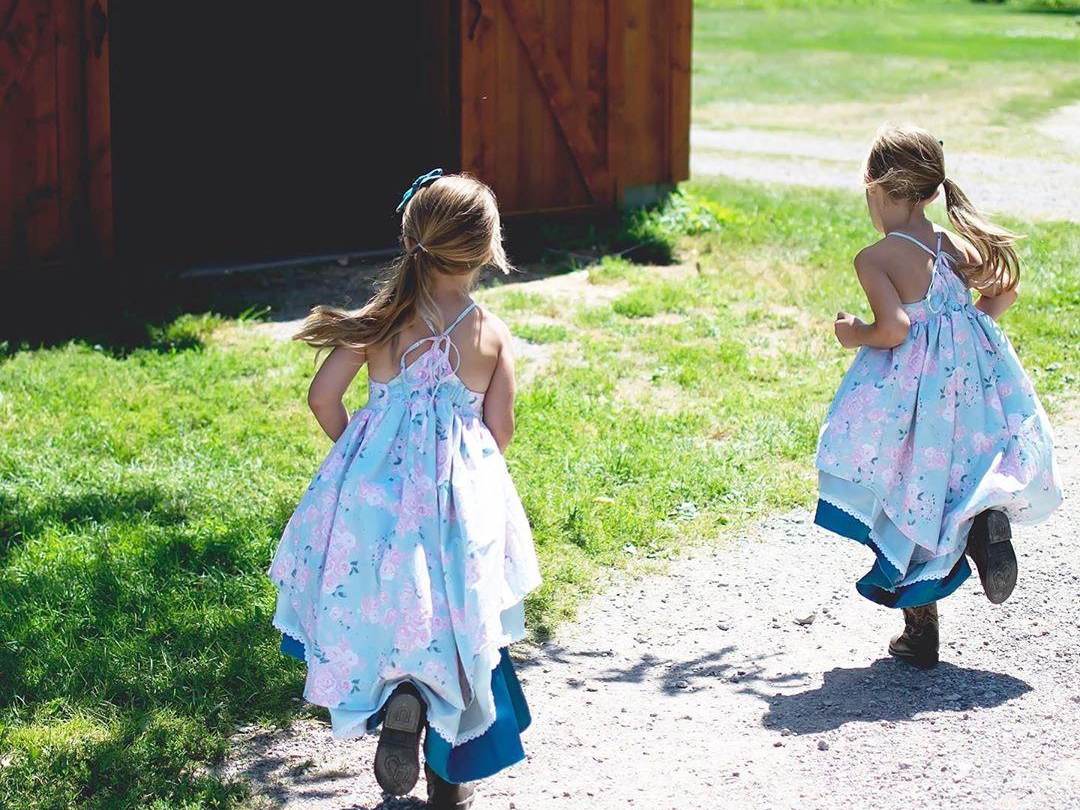 Two little girls in sundresses running toward a barn on Grandpa Tiny's Farm in Frankenmuth