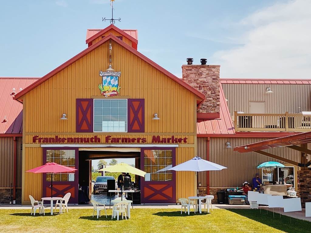 Frankenmuth Farmers Market barn with tables and sun umbrellas outside