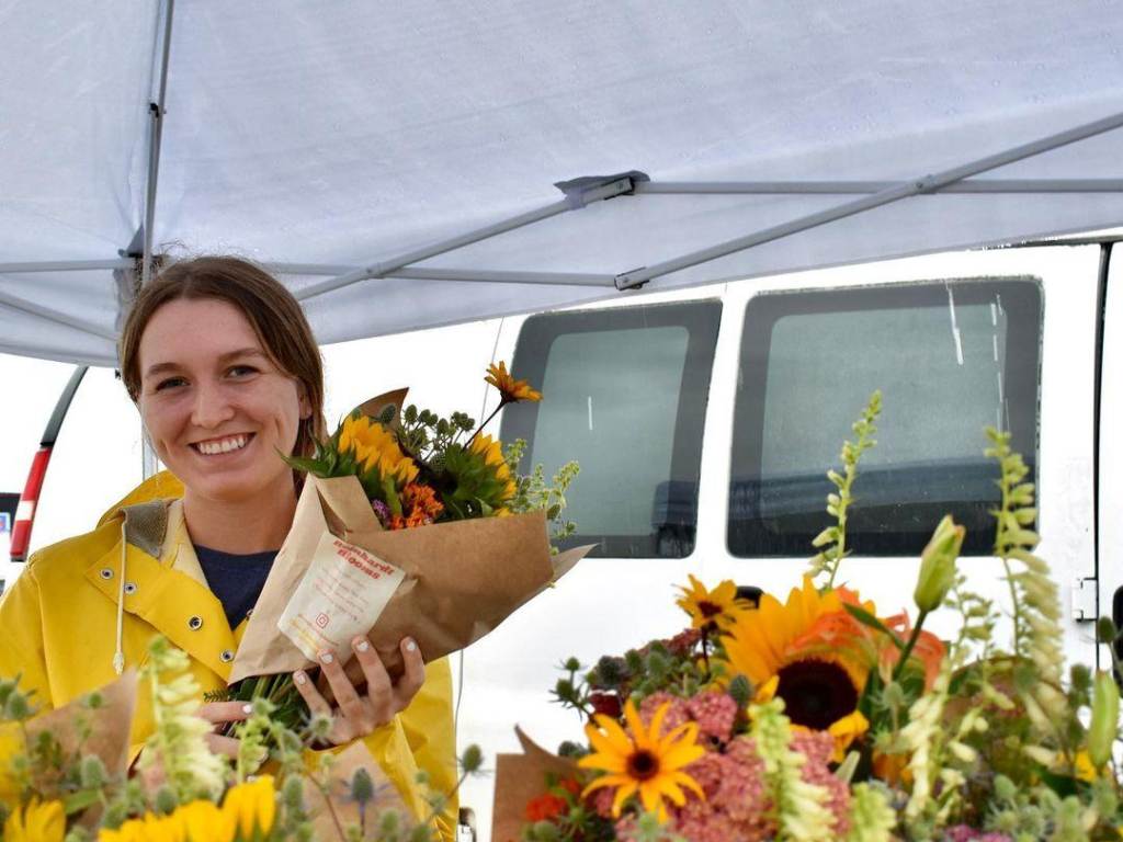 Woman smiling while selling sunflower bouquets from Reinhardt Blooms at the Midland Area Farmers Market in Midland
