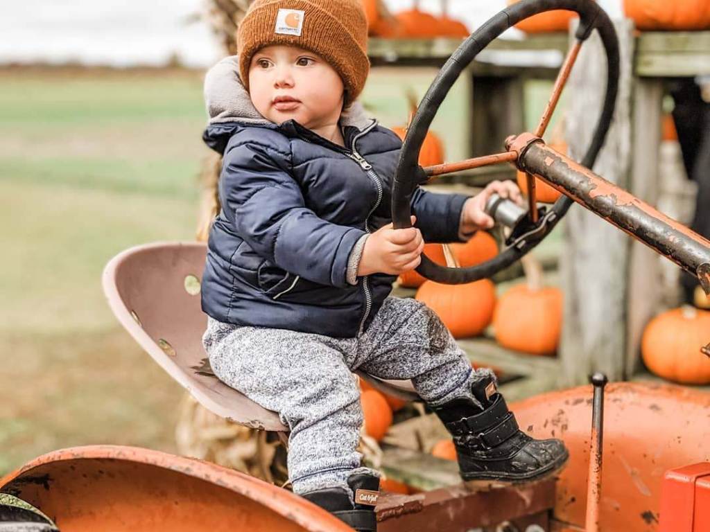 Little boy sitting on an antique tractor at Johnson's Giant Pumpkins in the fall