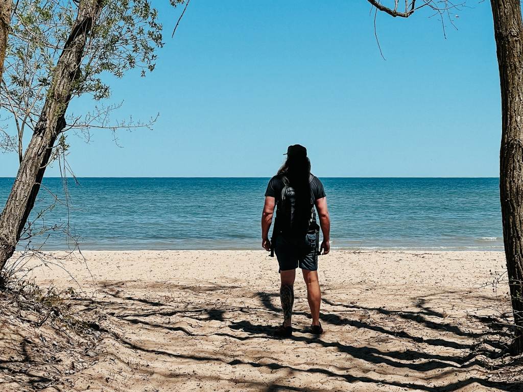 Guy standing on the beach at Bay City State Park in Bay City, looking out at the water