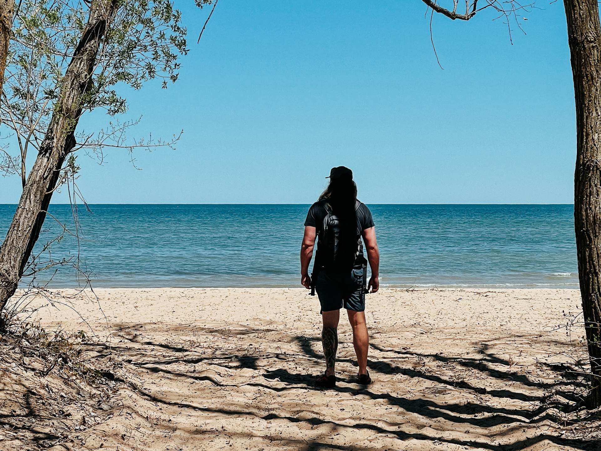 Guy standing on the beach at Bay City State Park in Bay City, looking out at the water
