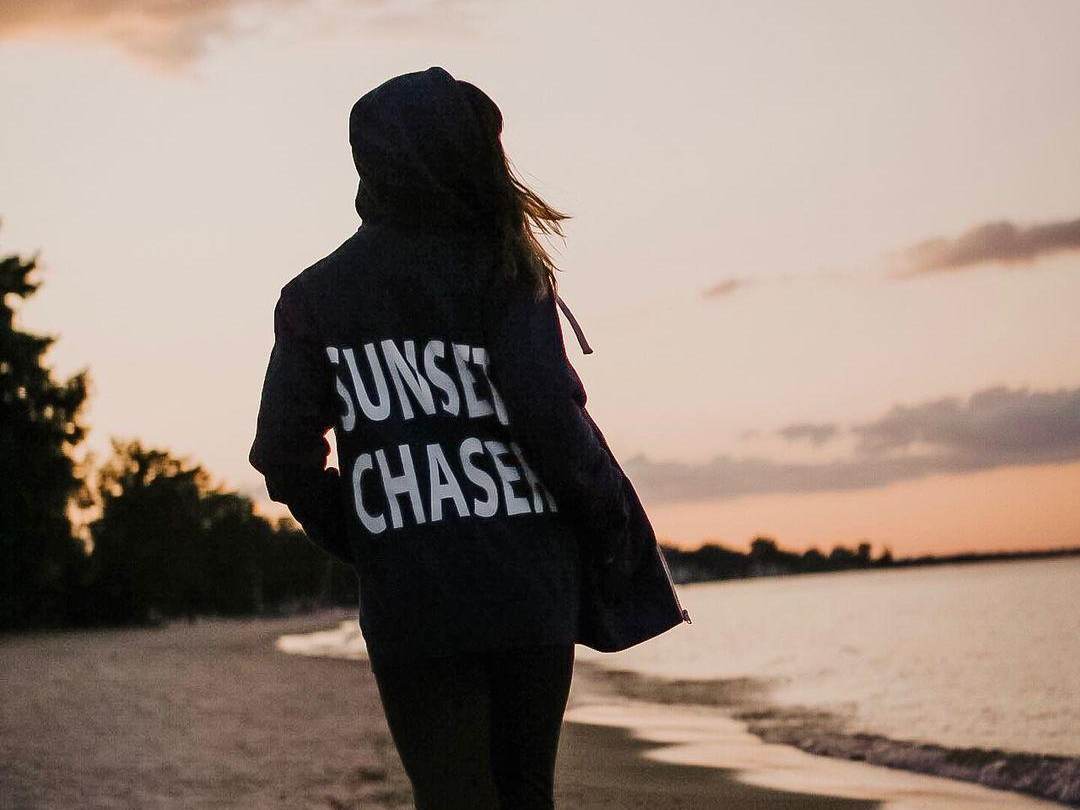 Woman standing on the beach near the water, watching the sun set at Bay City State Park