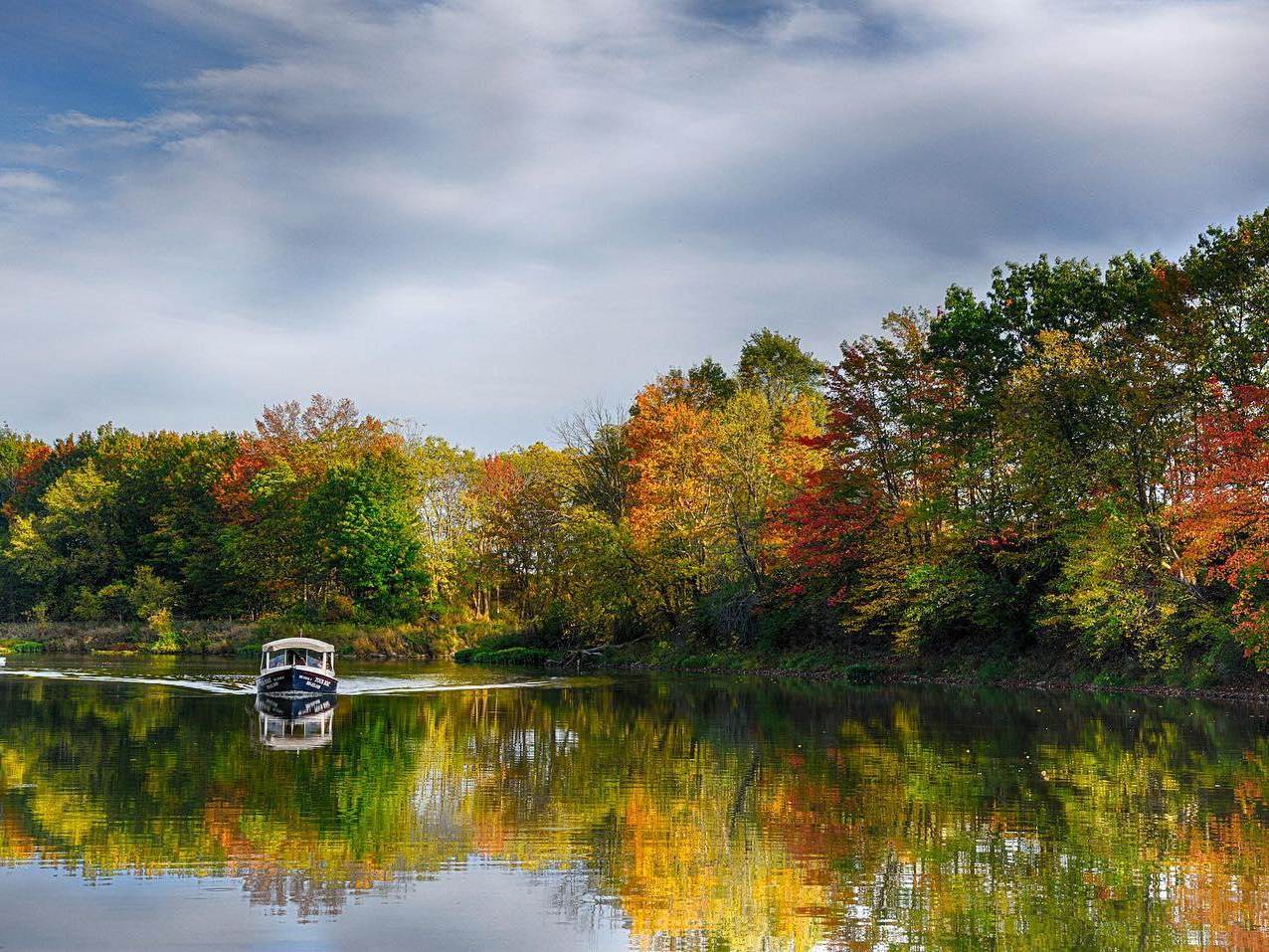 Frankenmuth FunShips boat gliding across the Cass River with fall-colored trees in the background