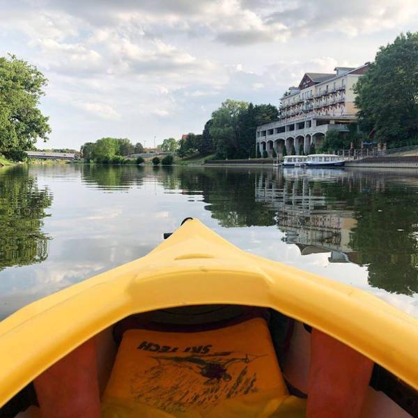 Views from a bright yellow kayak on the Cass River in Frankenmuth, with the Marv Herzog Hotel reflected on the water