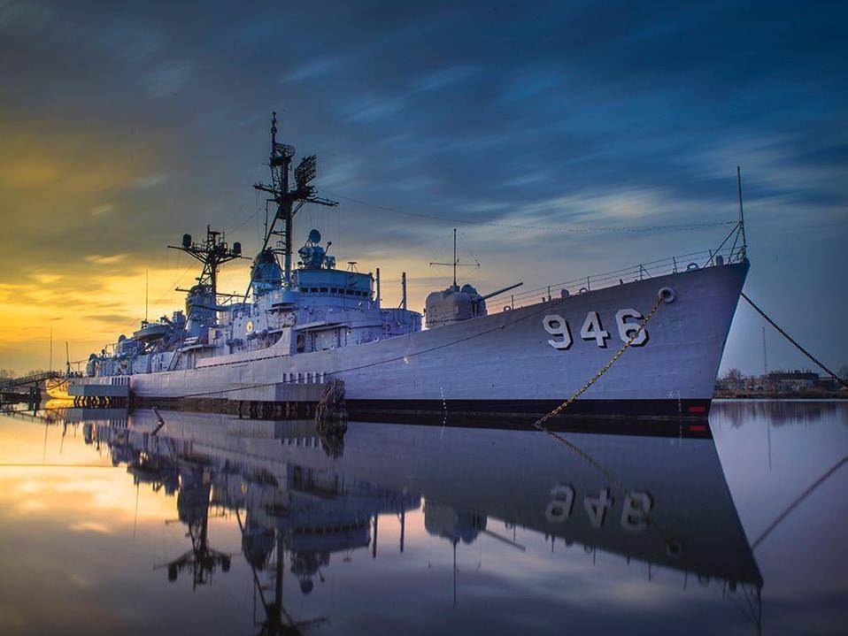 USS Edson reflecting off the water in Bay City with a blue-orange sky behind